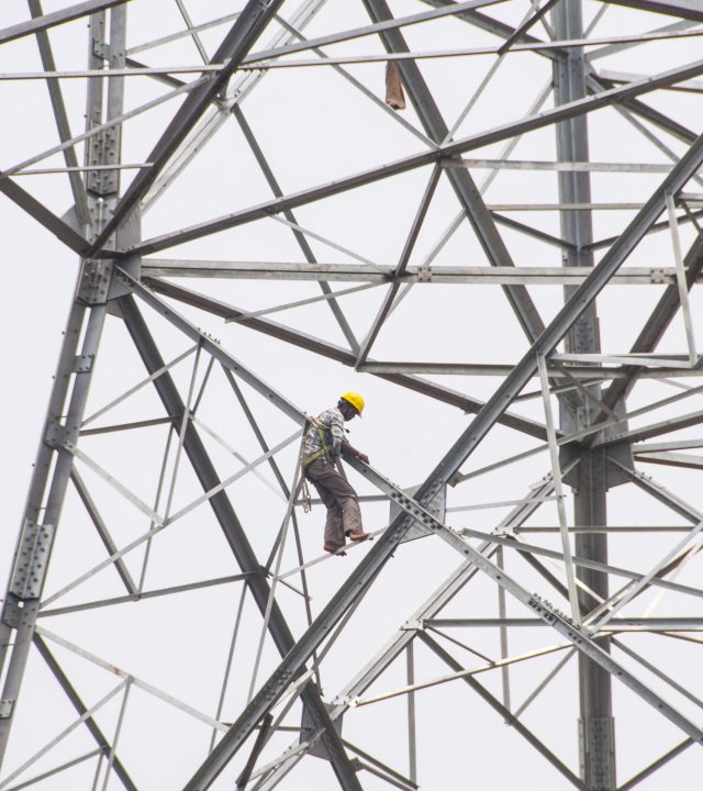 Pylon construction workers working on the top of power tower.